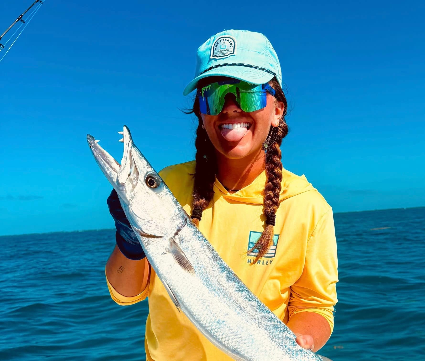 Brittany Lynn Armstrong smiling on a boat while holding a freshly caught fish on a bright, clear day.